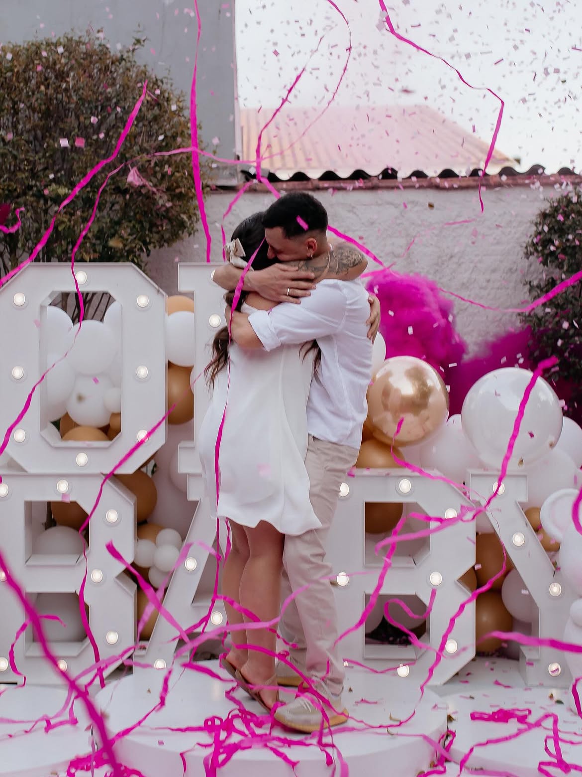 Chá revelação com confetes rosa e casal emocionado